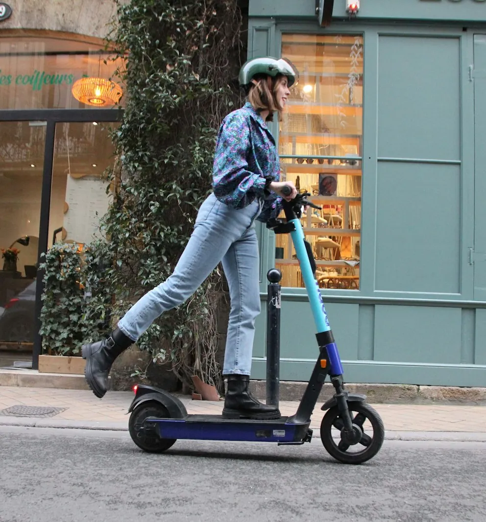 Pessoa de capacete a andar de trotinete elétrica numa rua da cidade